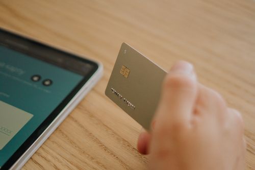A hand holding a credit card beside a smartphone