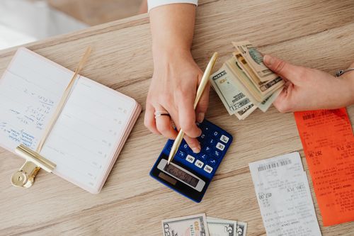 Hands budgeting cash with a calculator and notebook