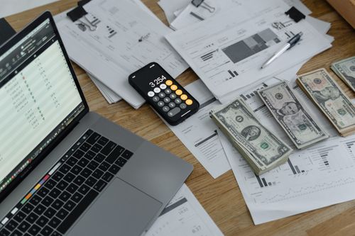 A laptop, calculator, and financial documents on a desk